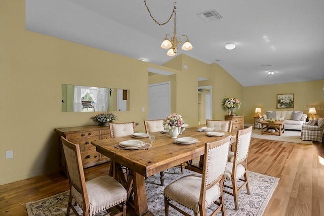 dining space featuring lofted ceiling, light hardwood / wood-style flooring, and a notable chandelier