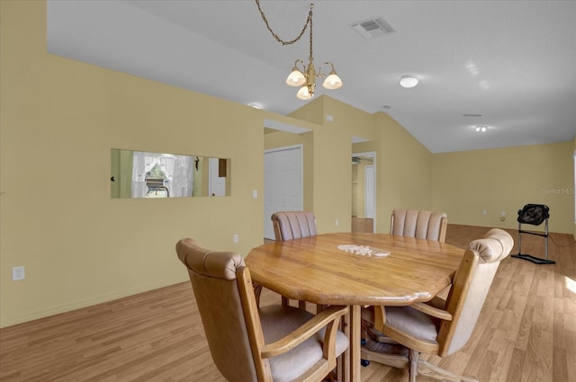 dining space with a notable chandelier, vaulted ceiling, and light wood-type flooring