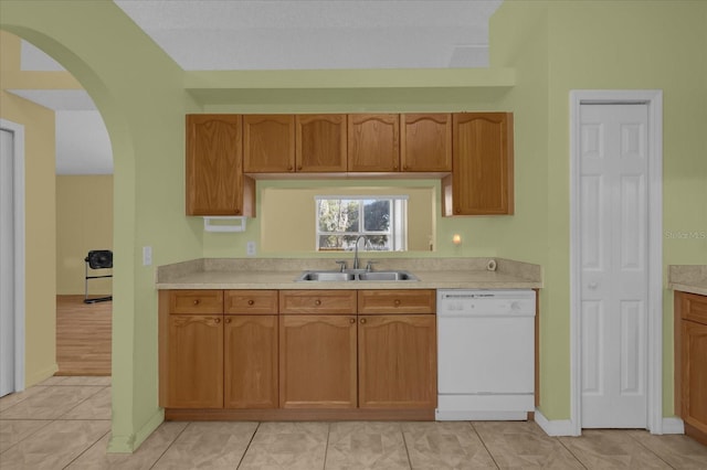 kitchen with white dishwasher, sink, and light tile patterned flooring