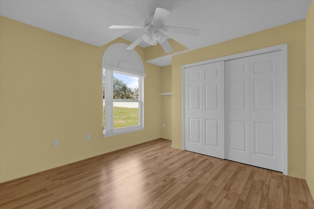 unfurnished bedroom with a closet, a textured ceiling, ceiling fan, and light hardwood / wood-style flooring