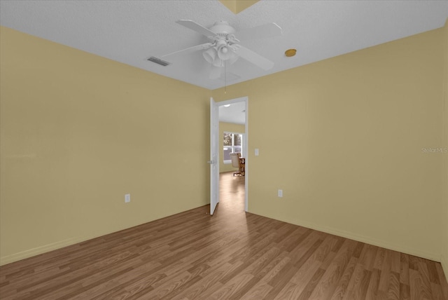 spare room with a textured ceiling, ceiling fan, and light hardwood / wood-style flooring