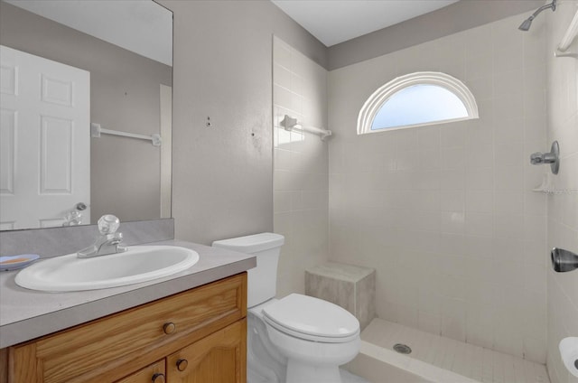 bathroom featuring vanity, tiled shower, and toilet