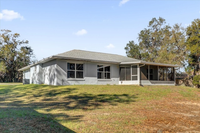 rear view of house featuring a yard and a sunroom