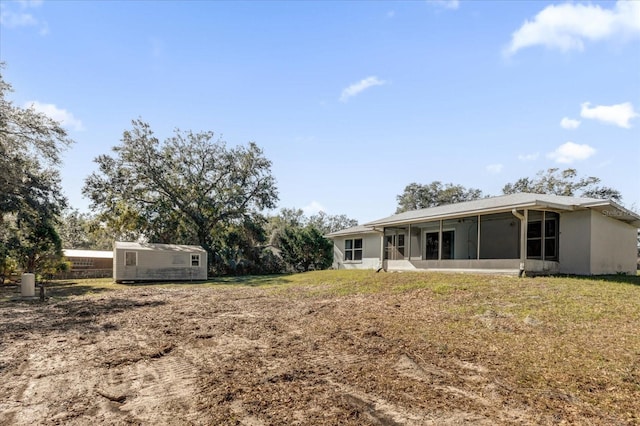 back of property featuring a sunroom, a lawn, and a shed