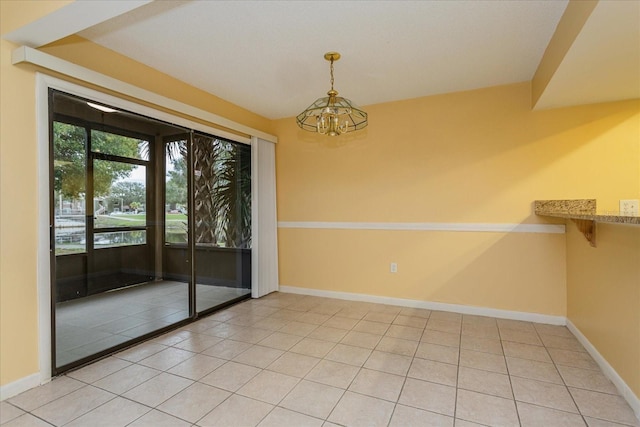 empty room with a notable chandelier and tile patterned floors