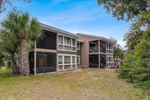 rear view of property with a sunroom and a yard