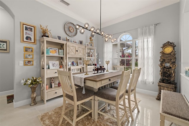 tiled dining area featuring ornamental molding and an inviting chandelier