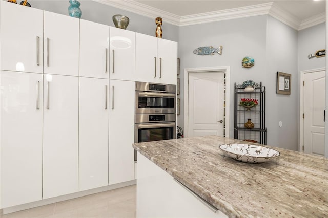 kitchen featuring white cabinetry, crown molding, stainless steel double oven, and light stone counters