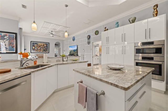 kitchen featuring appliances with stainless steel finishes, pendant lighting, sink, white cabinets, and a center island