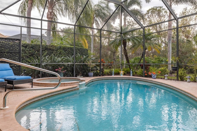 view of pool with a patio area, an in ground hot tub, and glass enclosure