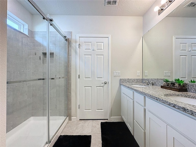 bathroom featuring tile patterned floors, a shower with shower door, vanity, and a textured ceiling