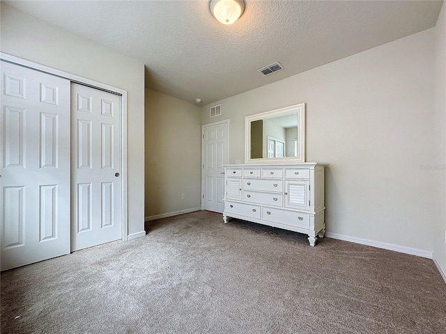 unfurnished bedroom with carpet, a textured ceiling, and a closet