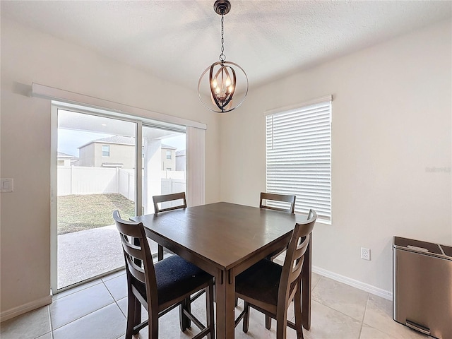 dining room featuring a healthy amount of sunlight, a chandelier, a textured ceiling, and light tile patterned floors