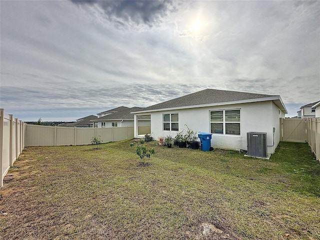 rear view of property with a yard and central air condition unit