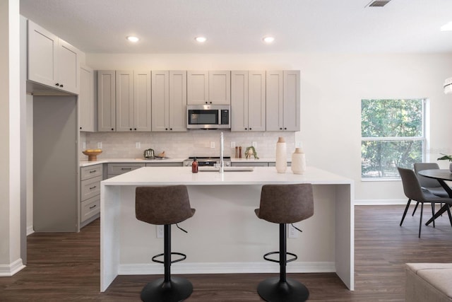 kitchen with decorative backsplash, dark hardwood / wood-style flooring, and a breakfast bar area