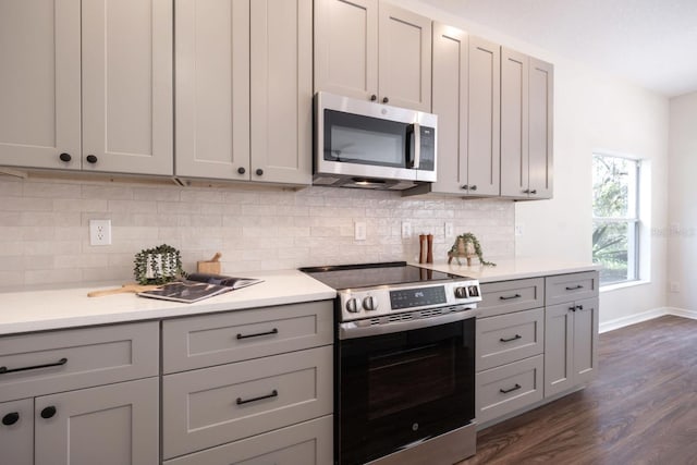 kitchen with dark hardwood / wood-style flooring, backsplash, gray cabinets, and stainless steel appliances