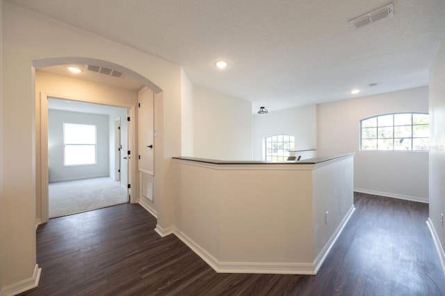 hall featuring dark wood-type flooring and a textured ceiling