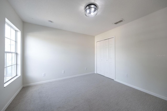 unfurnished bedroom featuring carpet flooring, a textured ceiling, and a closet