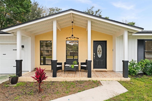 view of exterior entry featuring a garage and covered porch