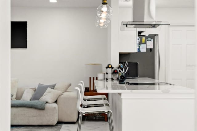 kitchen with stainless steel refrigerator, ventilation hood, white cabinets, decorative light fixtures, and kitchen peninsula