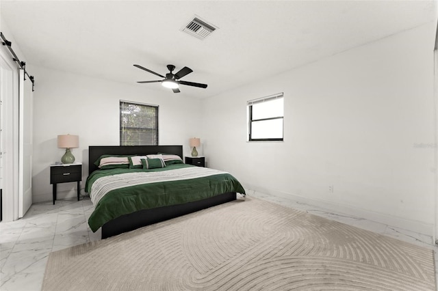 bedroom featuring multiple windows, a barn door, and ceiling fan