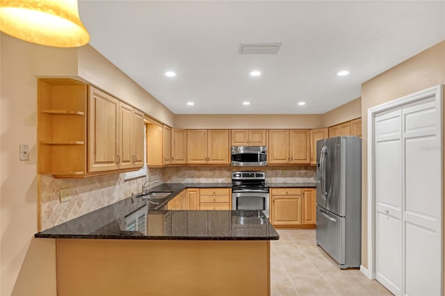 kitchen featuring tasteful backsplash, kitchen peninsula, dark stone countertops, and appliances with stainless steel finishes