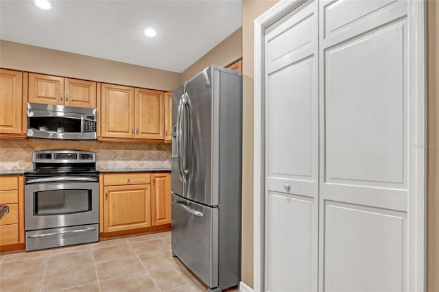 kitchen with tasteful backsplash, appliances with stainless steel finishes, light tile patterned floors, and dark stone counters