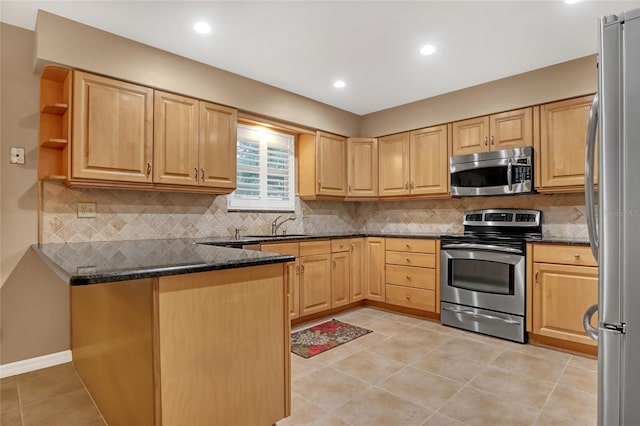 kitchen featuring sink, light tile patterned floors, appliances with stainless steel finishes, dark stone countertops, and decorative backsplash