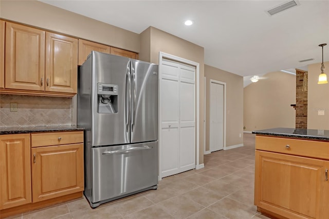 kitchen featuring stainless steel fridge with ice dispenser, hanging light fixtures, light tile patterned floors, dark stone counters, and decorative backsplash