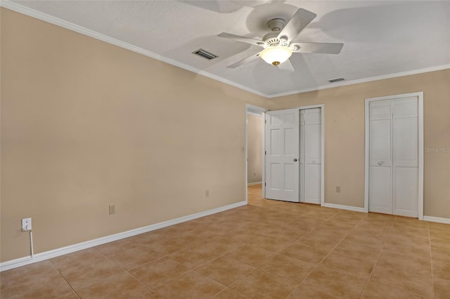 unfurnished bedroom featuring light tile patterned floors, ceiling fan, ornamental molding, a textured ceiling, and two closets