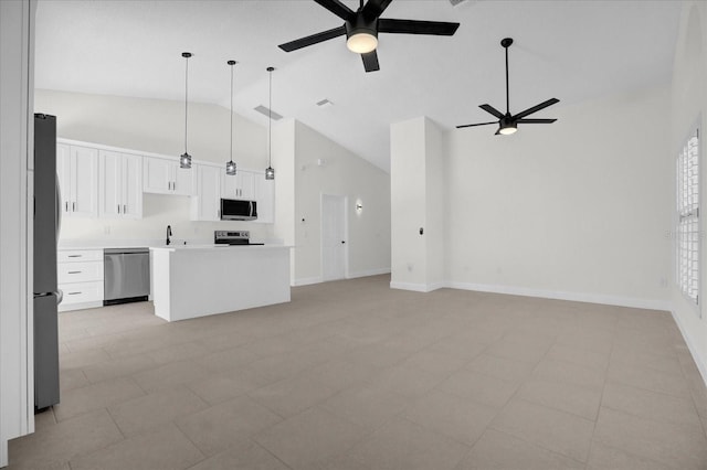 kitchen with open floor plan, hanging light fixtures, stainless steel appliances, light countertops, and white cabinetry