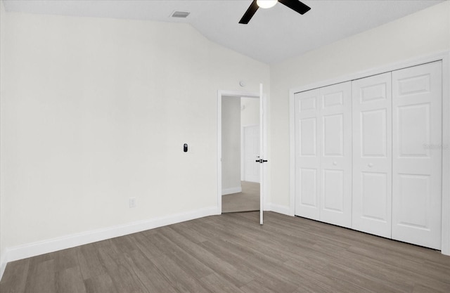 unfurnished bedroom with baseboards, visible vents, ceiling fan, vaulted ceiling, and light wood-style floors