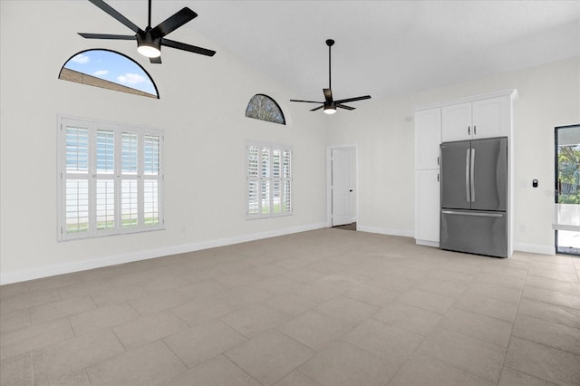 unfurnished living room with high vaulted ceiling, baseboards, and a ceiling fan