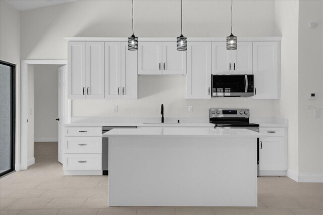 kitchen featuring white cabinets, pendant lighting, stainless steel appliances, and light countertops