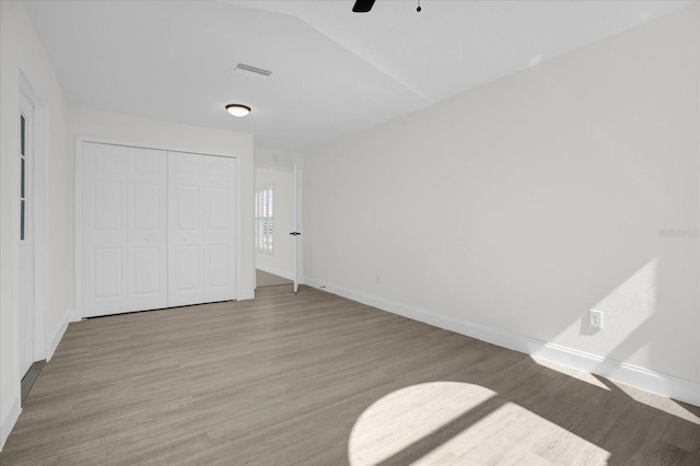 unfurnished bedroom with baseboards, light wood-style flooring, visible vents, and a closet