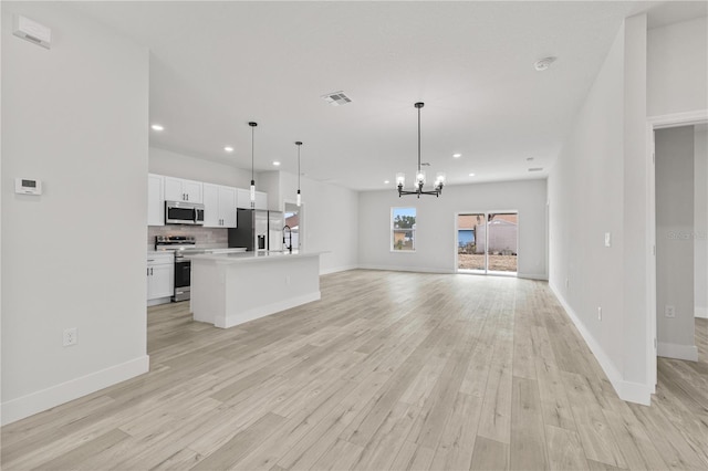 kitchen with white cabinets, decorative backsplash, hanging light fixtures, a center island, and stainless steel appliances