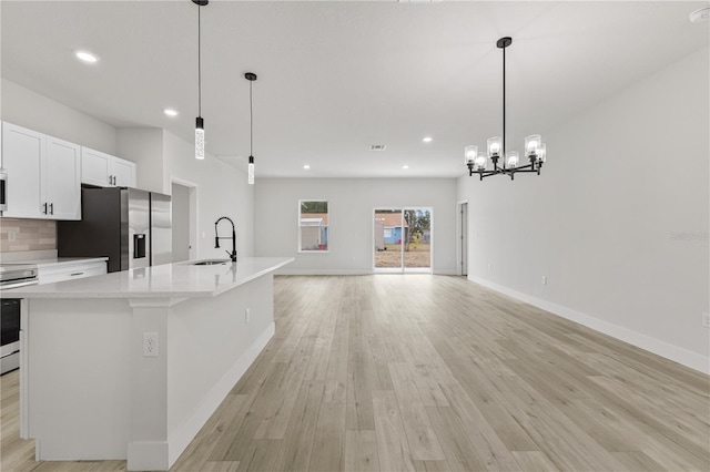 kitchen with sink, tasteful backsplash, white cabinetry, hanging light fixtures, and appliances with stainless steel finishes