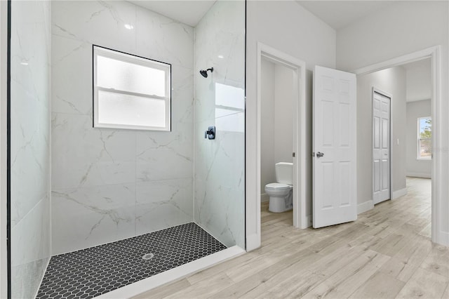 bathroom featuring a healthy amount of sunlight, toilet, and a tile shower