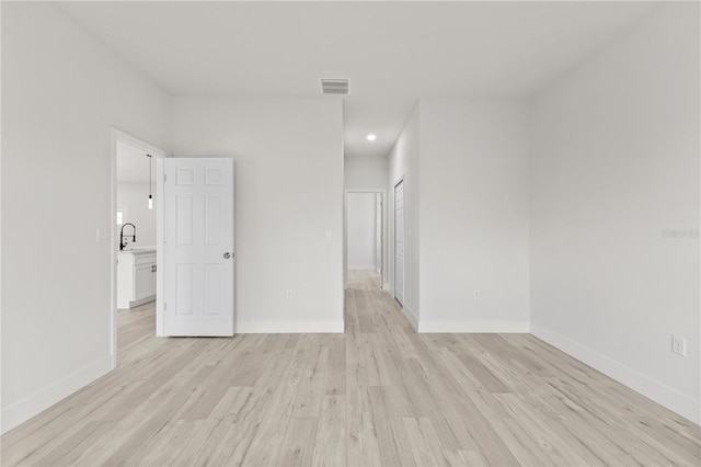 spare room featuring sink and light wood-type flooring