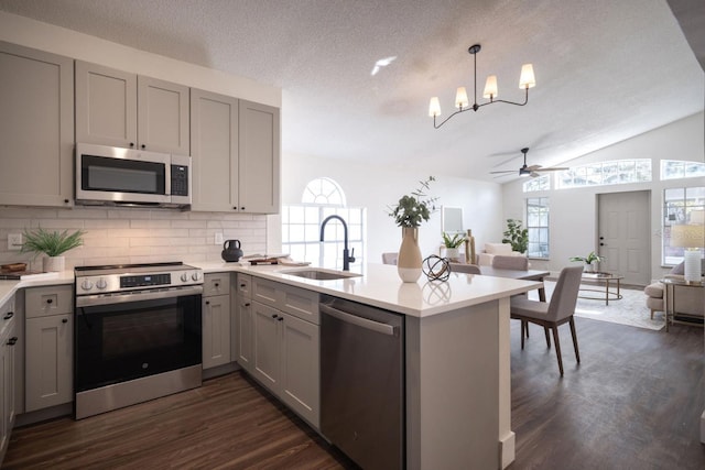 kitchen with decorative light fixtures, sink, gray cabinetry, kitchen peninsula, and stainless steel appliances