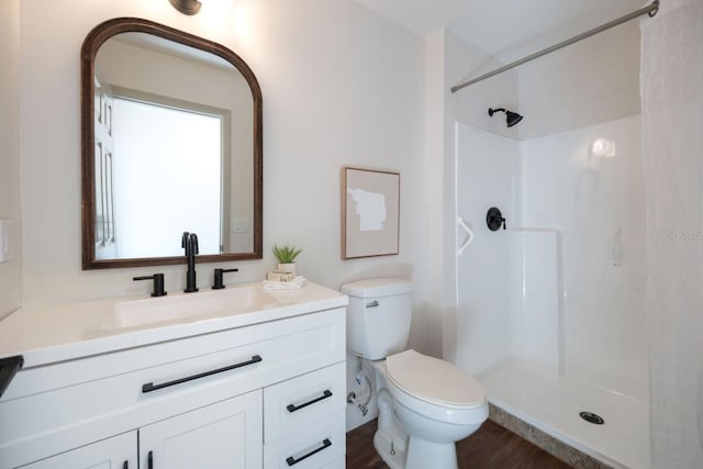 bathroom featuring hardwood / wood-style flooring, vanity, a shower, and toilet