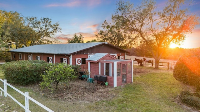 property exterior at dusk with an outdoor structure and a lawn