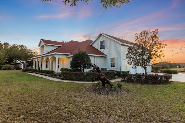 property exterior at dusk featuring covered porch and a lawn