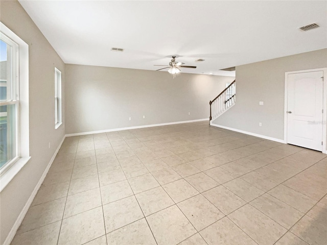 empty room with ceiling fan and light tile patterned floors