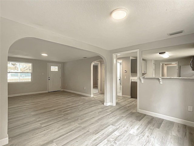 unfurnished living room featuring a textured ceiling and light wood-type flooring