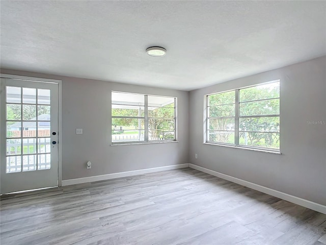 unfurnished room with a textured ceiling and light hardwood / wood-style floors