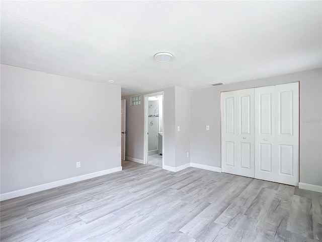 unfurnished bedroom with ensuite bath, light hardwood / wood-style flooring, and a closet