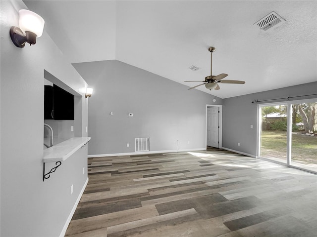 unfurnished living room with hardwood / wood-style flooring, vaulted ceiling, and ceiling fan