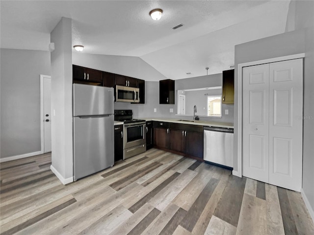 kitchen with appliances with stainless steel finishes, sink, lofted ceiling, and dark brown cabinetry