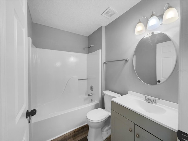 full bathroom with tub / shower combination, vanity, wood-type flooring, a textured ceiling, and toilet